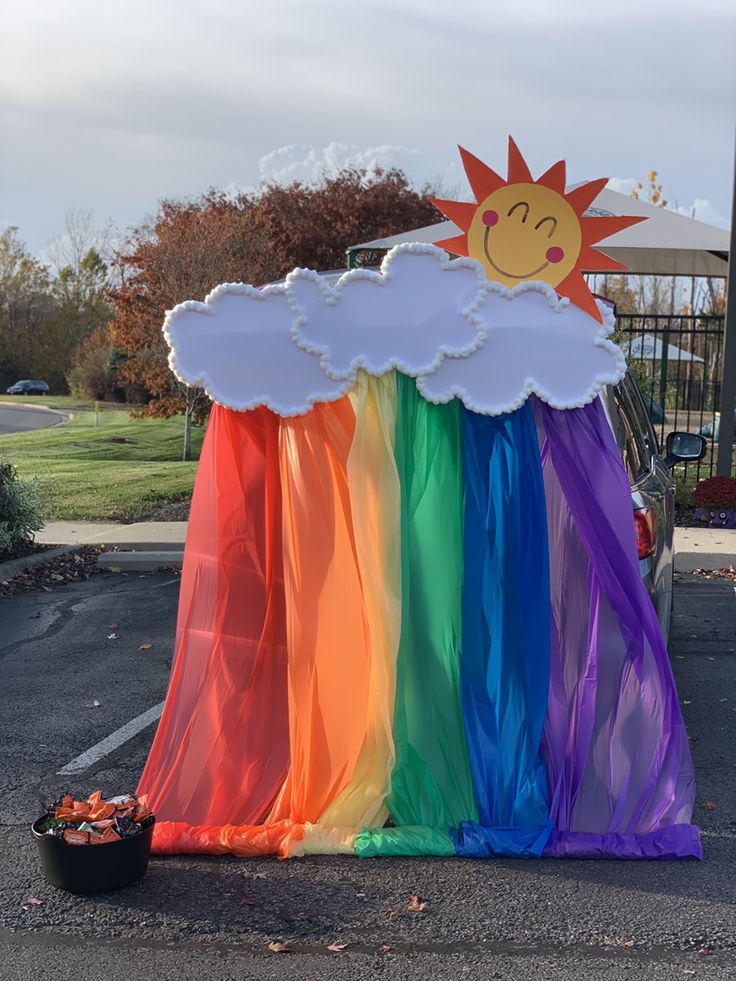 a rainbow colored tent with a smiling sun on it's face and clouds in the sky