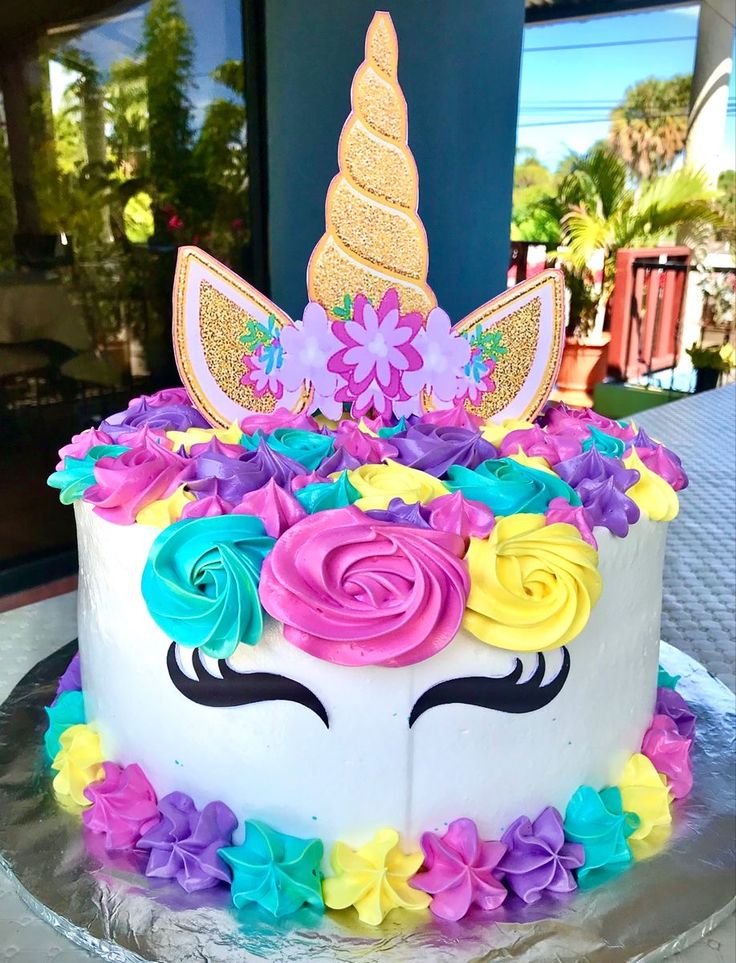 a cake decorated with flowers and a unicorn's face