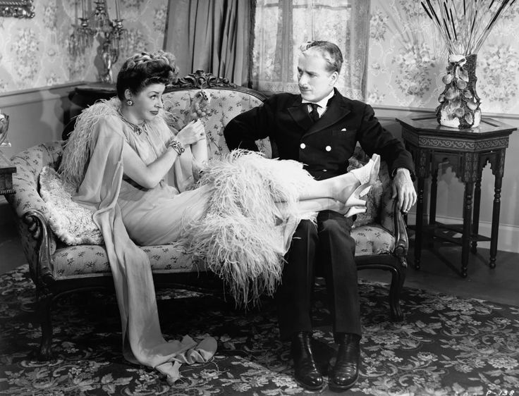 an old black and white photo of a man and woman sitting on a couch together