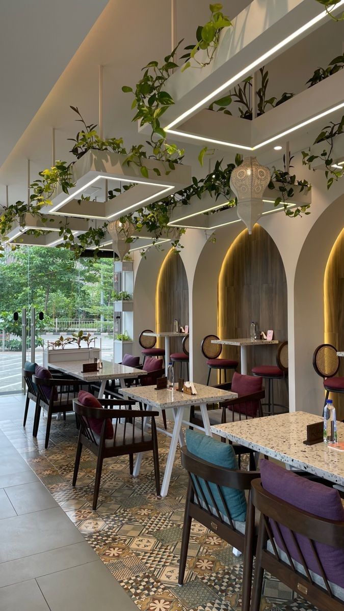 a restaurant with tables and chairs covered in plants