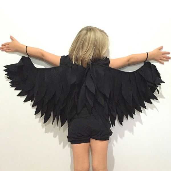 a woman with her arms spread out in front of a white wall wearing an angel wings costume