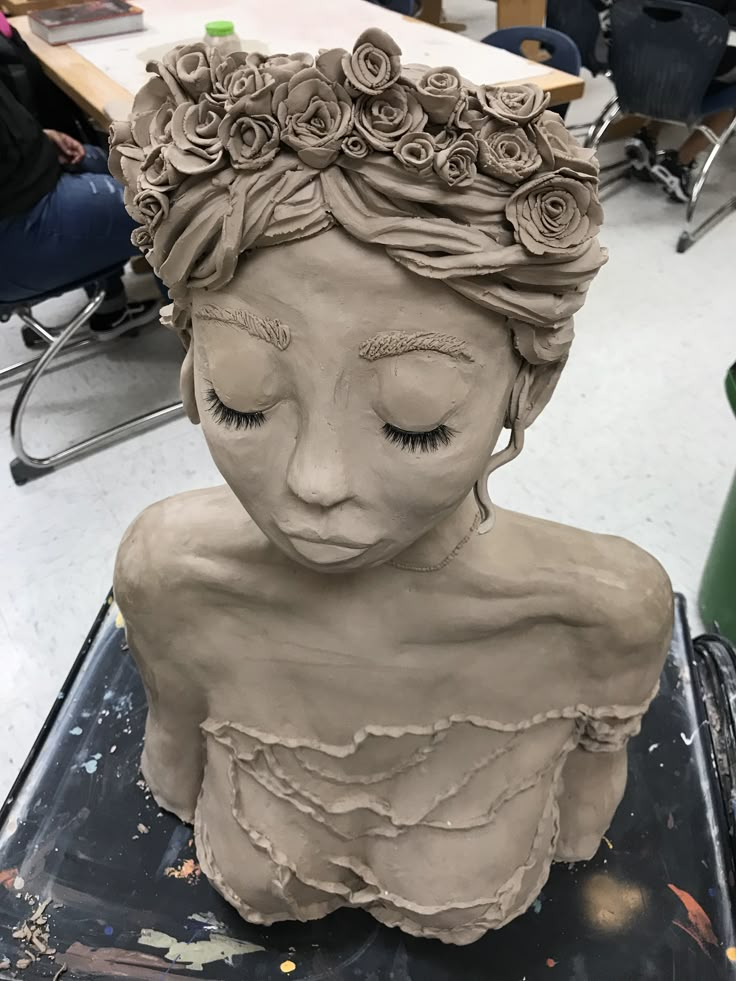 a clay sculpture of a woman with flowers in her hair