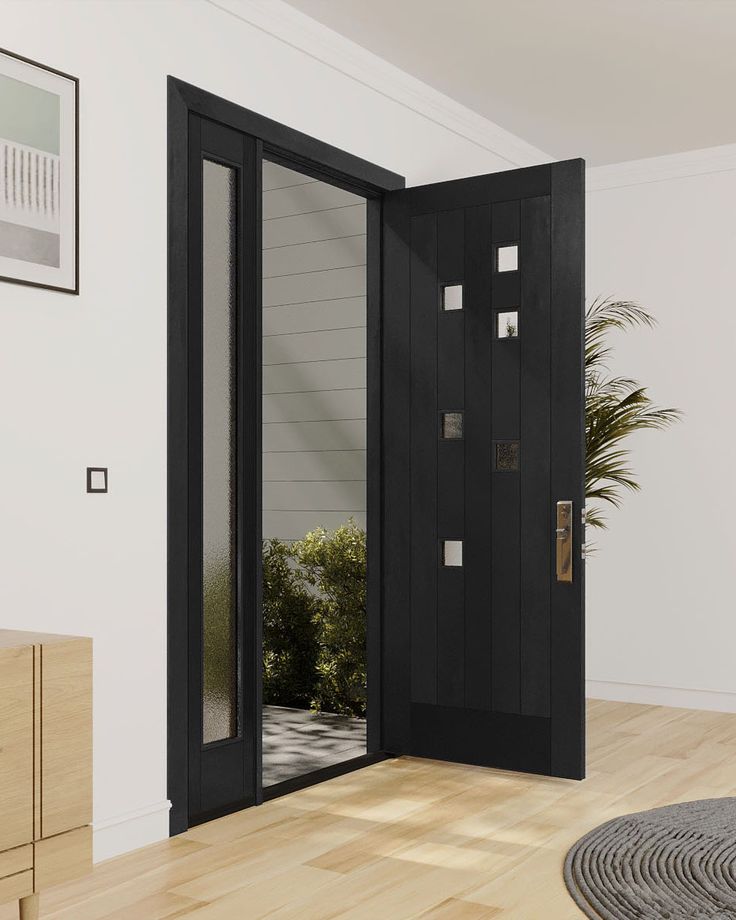 an open black door in a white room with wood flooring and potted plant