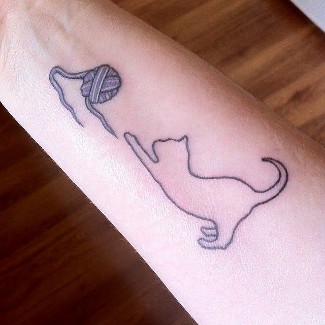 a cat with a ball of yarn on it's back arm tattooing the word love