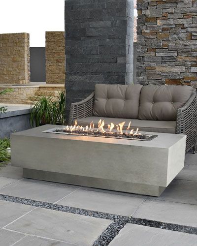 a fire pit sitting on top of a stone floor next to a couch and table