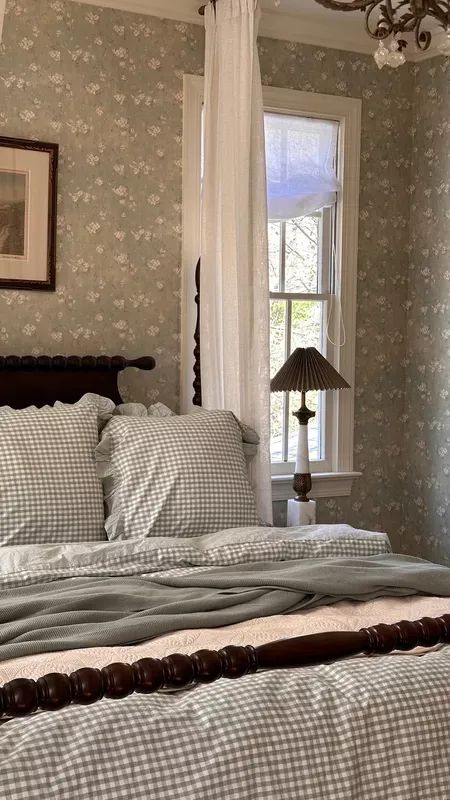 a bed sitting under a window next to a lamp on top of a wooden headboard