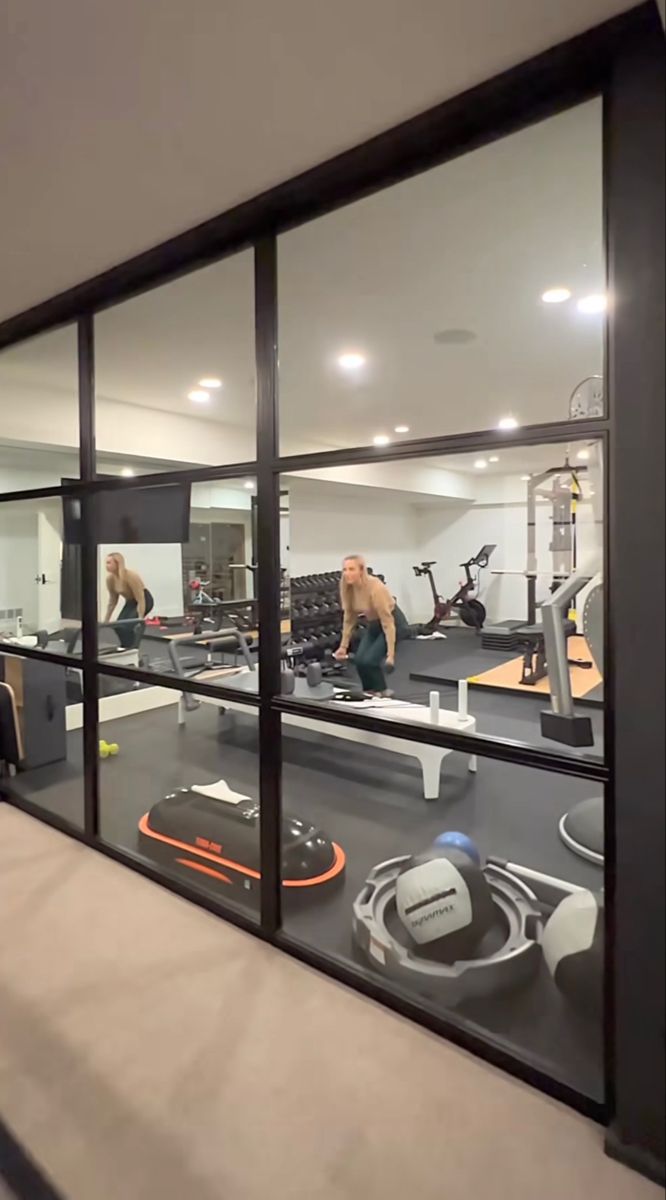 the reflection of two men in a mirror at an exercise room with treadmills and other equipment