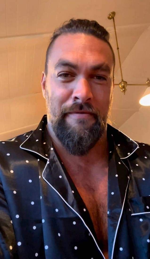 a man with a beard wearing a black and white polka dot shirt looking at the camera