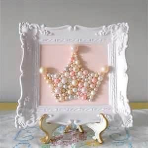 a white frame holding a pink and gray beaded star ornament with pearls