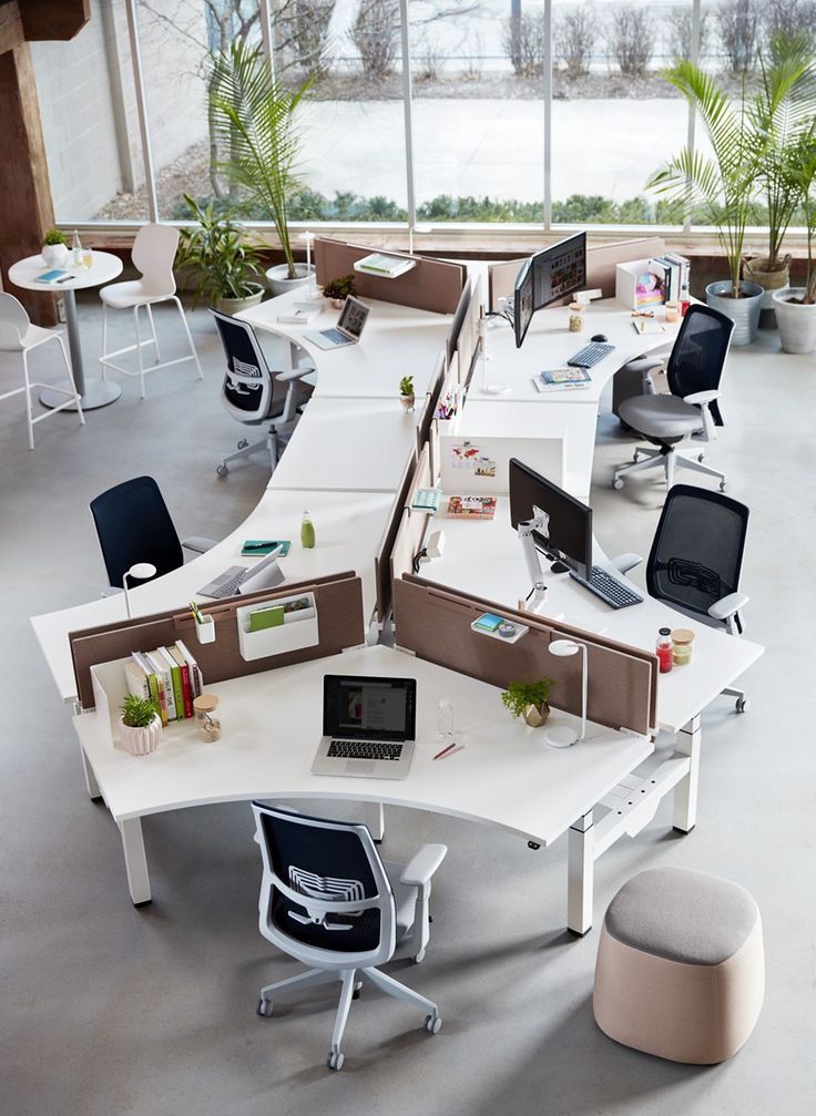 an office cubicle with multiple desks and chairs in the center, along with two computers