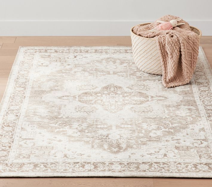 a beige and white area rug with an ornate design on the floor next to a basket