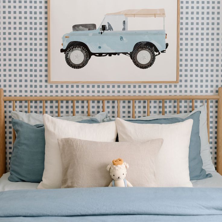 a blue truck is on the wall above a bed with pillows and a teddy bear