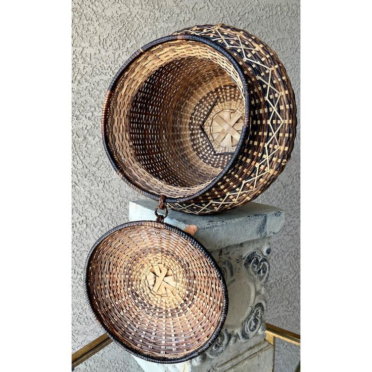 two woven baskets sitting on top of a stone pillar in front of a wall and stairs