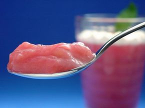 a close up of a spoon with food on it and a drink in the background