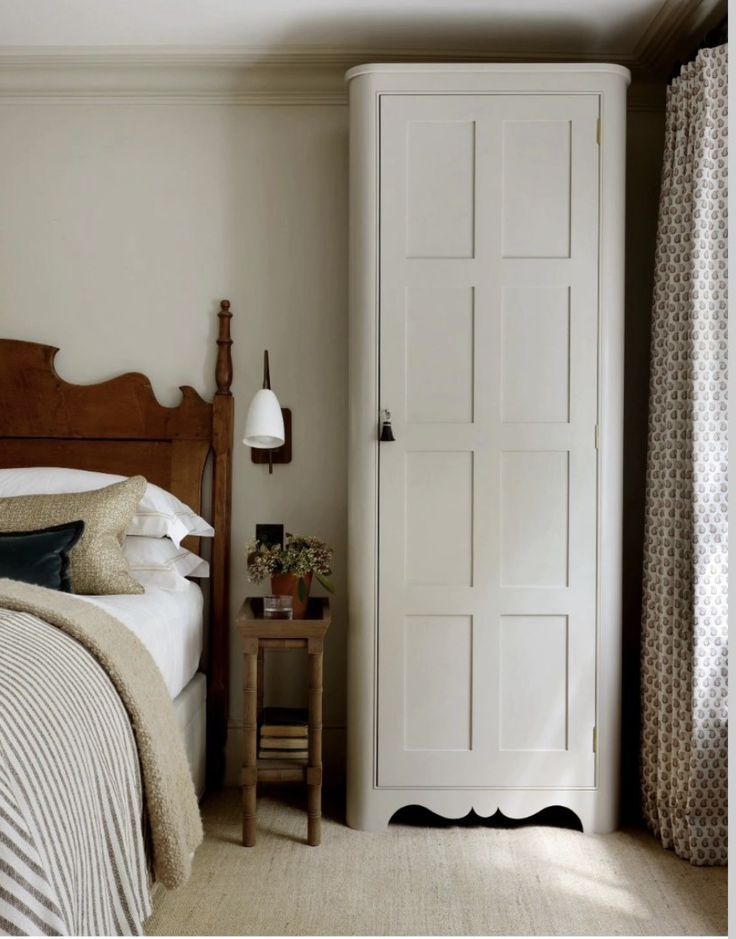 a bedroom with a bed, nightstand and white cupboards in it's corner