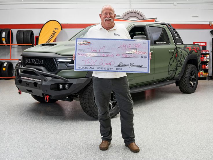 a man holding a large check in front of a truck