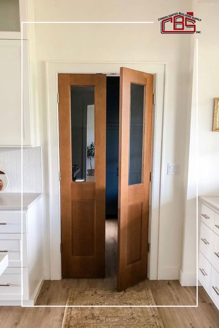 an open door in the middle of a room with white cabinets and drawers on either side