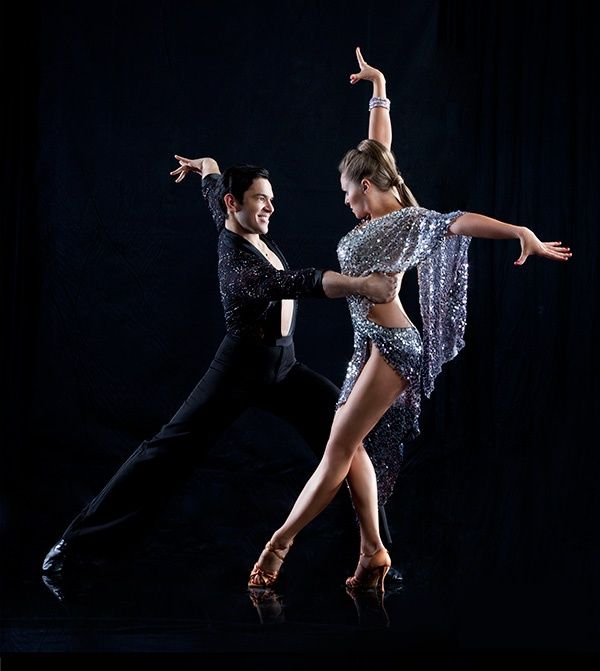 two dancers in black and silver outfits are dancing