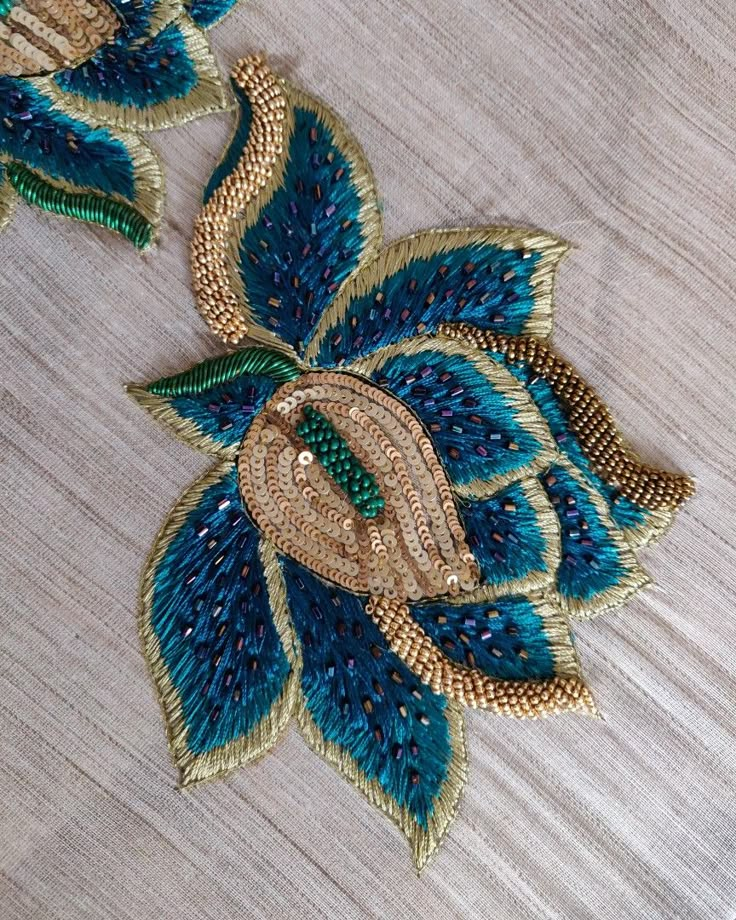 a blue and gold flower on a white table cloth with some beading around it