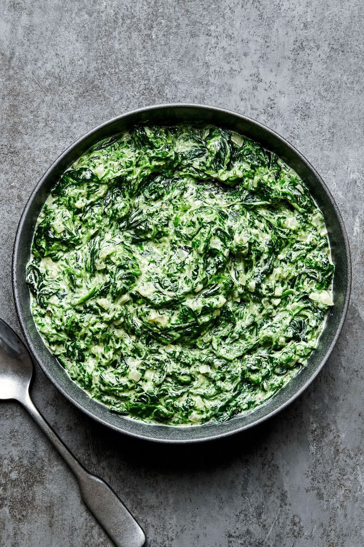 spinach in a skillet with two spoons next to it