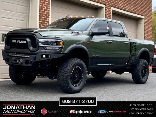 a green ram truck parked in front of a garage