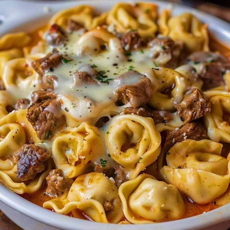 a white bowl filled with pasta and meat covered in sauce