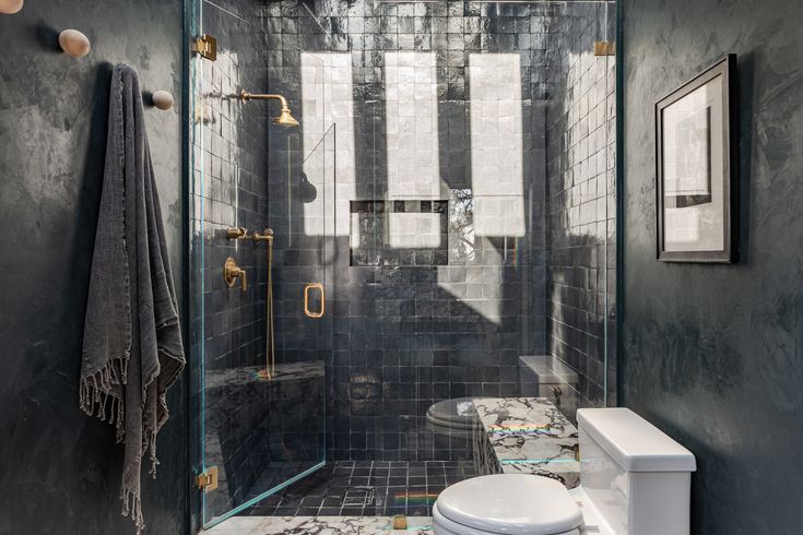 a bathroom with black and white tiles on the floor, walls and shower stall area