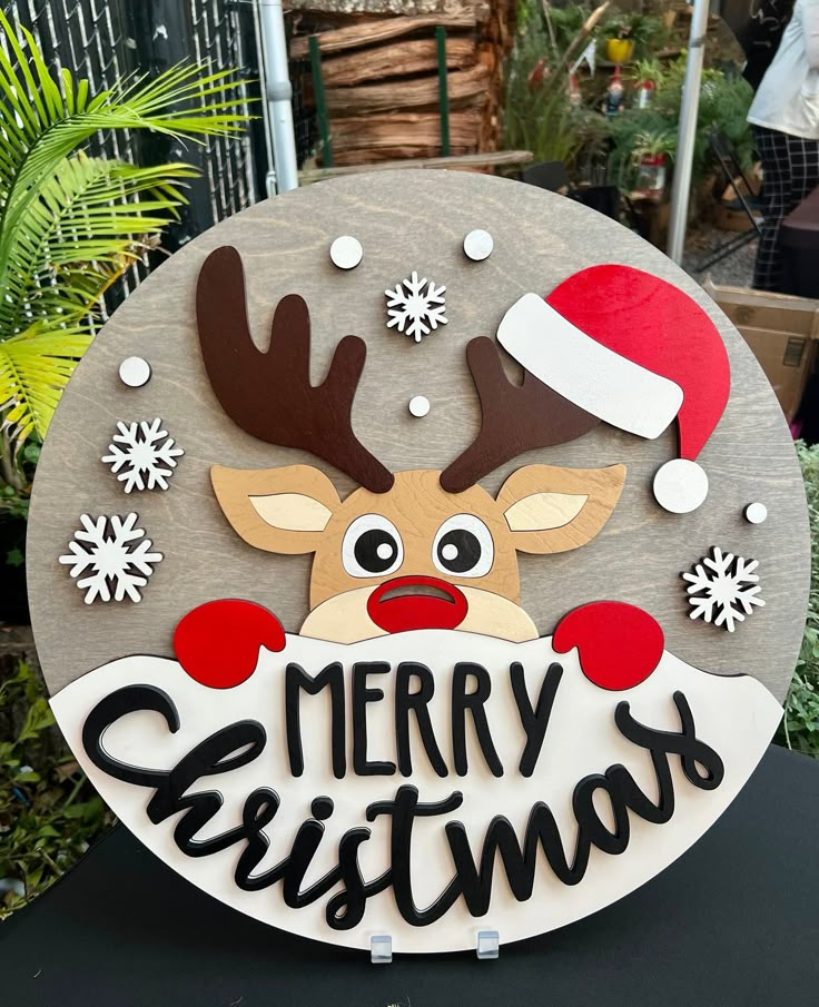 a merry christmas sign with a reindeer wearing a santa hat