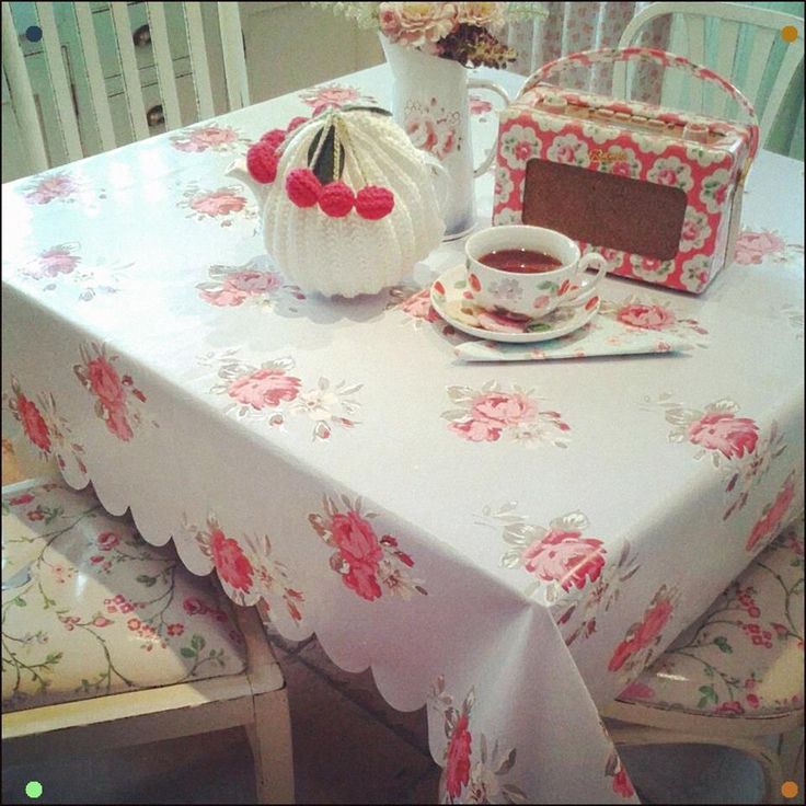 the table is covered with pink flowers and has a tea pot on top of it