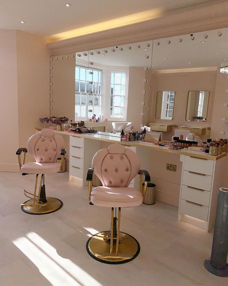 two pink chairs sitting in front of a mirror on top of a white countertop