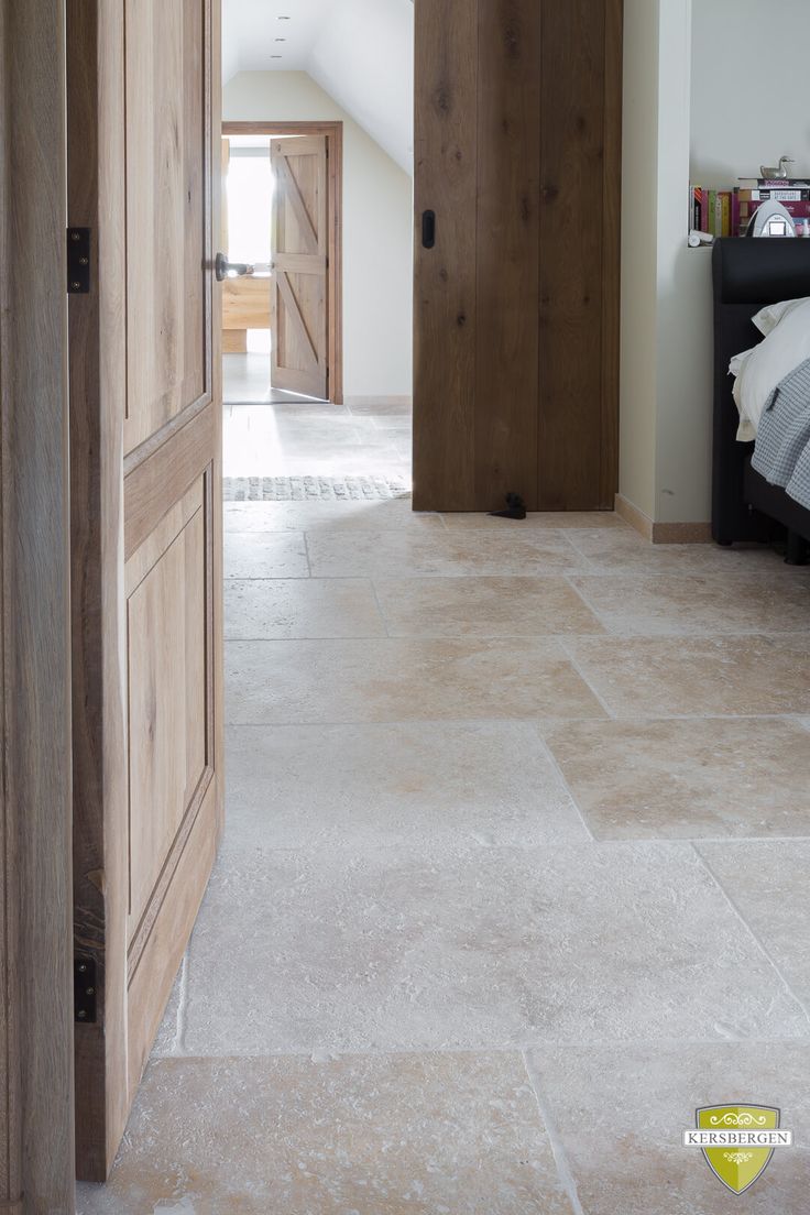 an open door leading into a bedroom with white walls and floor tiles on the floor