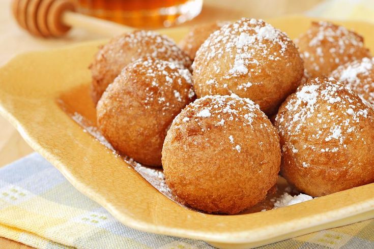 there are some powdered donuts in a yellow bowl on the table next to honey