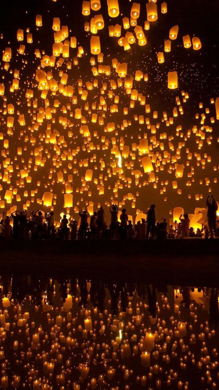 many lit up lanterns floating in the air