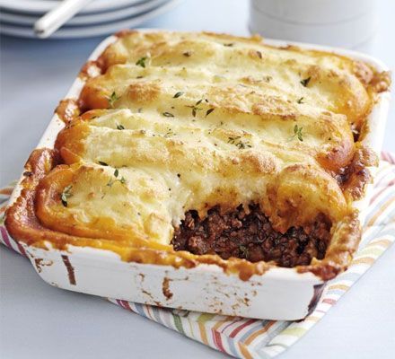 a casserole dish with meat and cheese in it sitting on a striped napkin