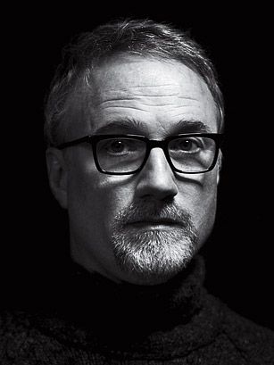 a black and white photo of a man in glasses looking at the camera with a serious look on his face