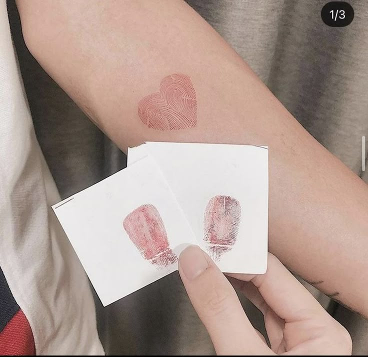 two finger prints on someone's arm that are both red and one is white