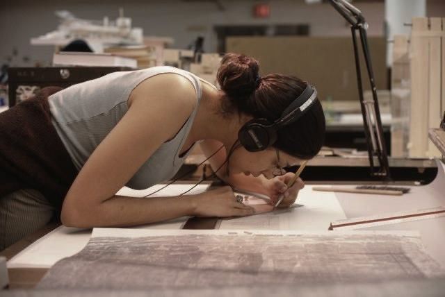 a woman in headphones is writing on a piece of paper while looking down at it