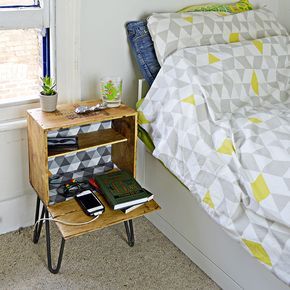 a small wooden table with books on it next to a bed