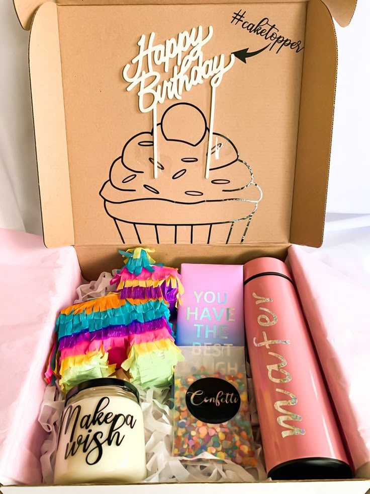 an open birthday box with cupcakes, candles and confetti in it