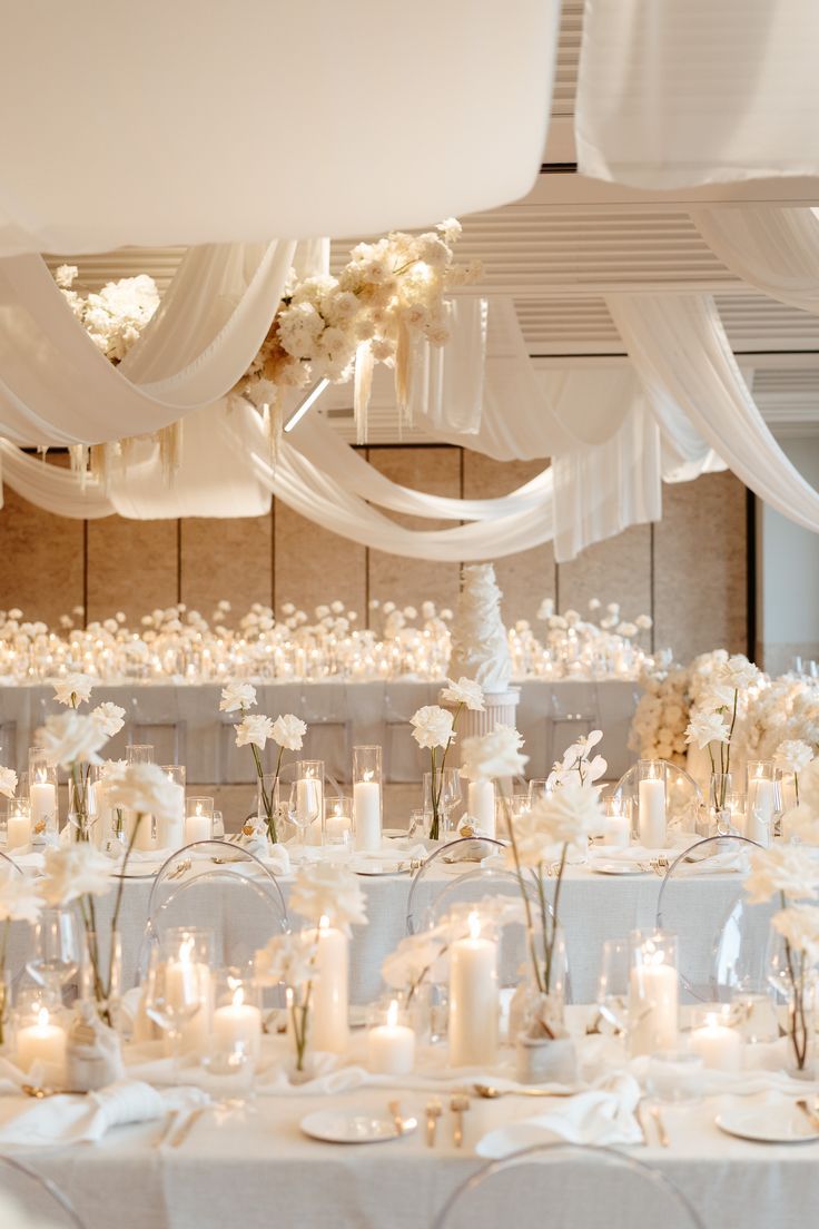 All white wedding. White Pillar Candles, white garden roses and orchids, and gold silverware. Off White Wedding Decorations, White Cream Ivory Wedding, Minimal Center Piece Wedding, White And Glass Wedding Decor, White Neutral Wedding Decor, Elegant Wedding Styling, White And Candle Wedding, Ivory Party Decorations, Rose Gold White Wedding Decor