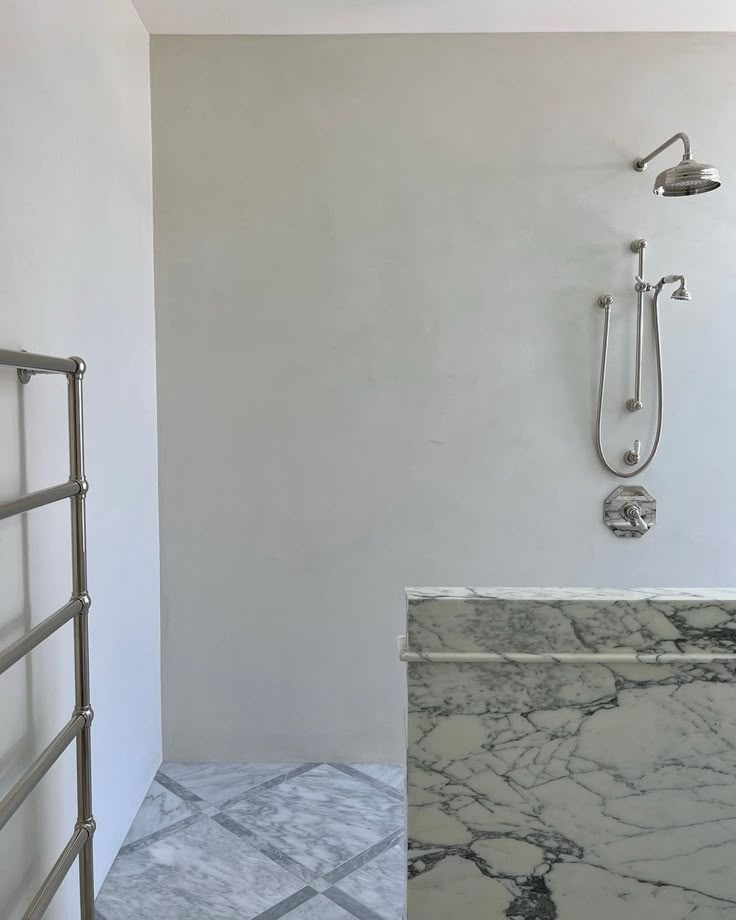 a bathroom with marble flooring and white walls, along with a walk in shower