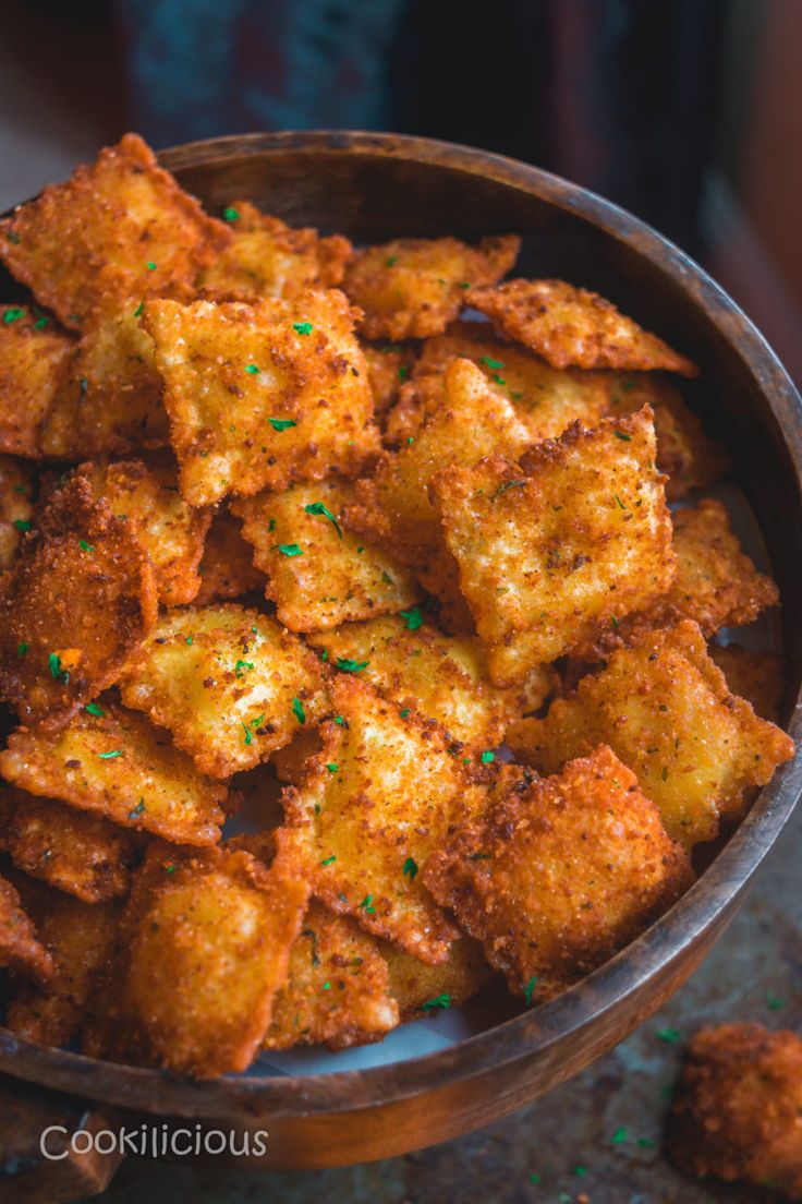 a wooden bowl filled with fried food on top of a table