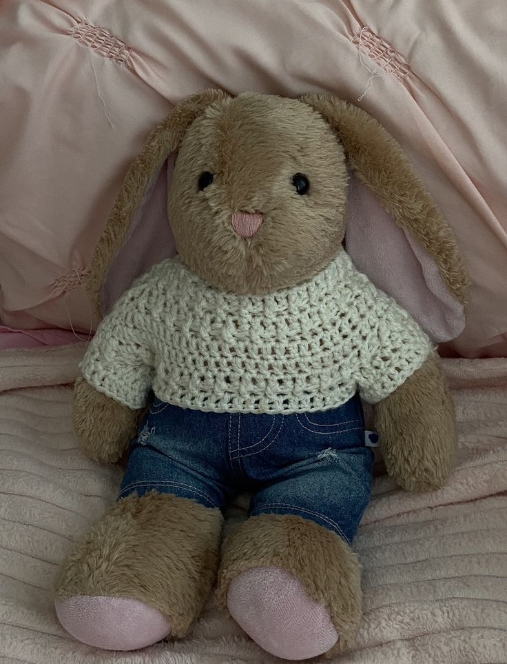 a stuffed animal bunny sitting on top of a bed