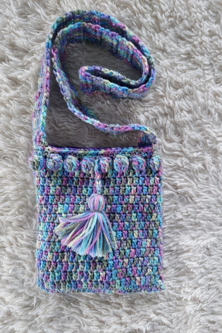 a multicolored crocheted bag with a tassel on the front and side