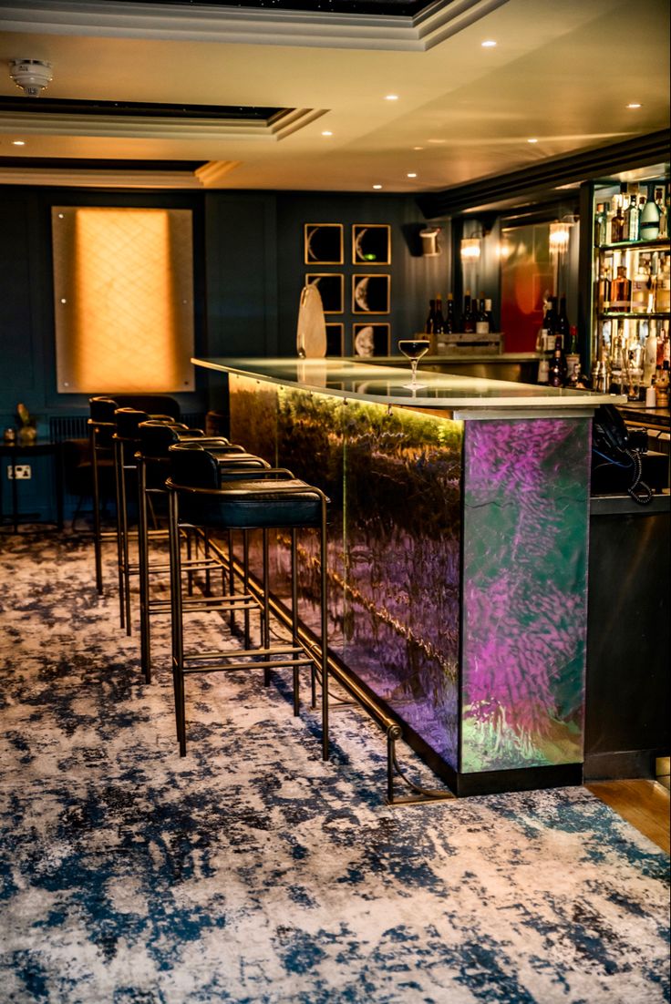 a bar with stools in front of it and an area rug on the floor