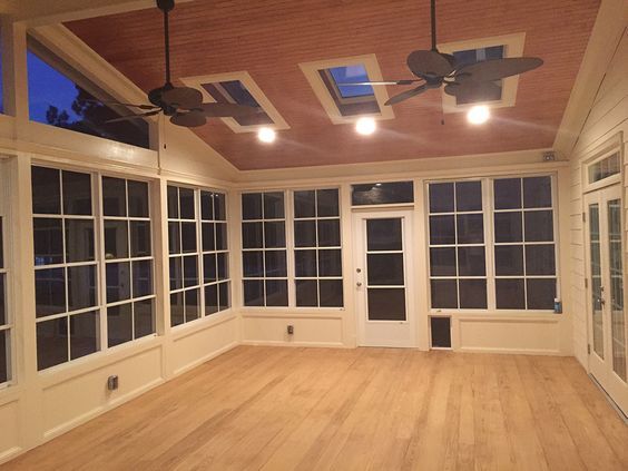 an empty room with large windows and ceiling fans on the ceiling is lit by three lights