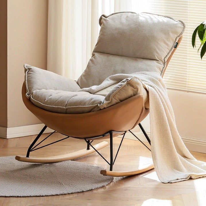 a rocking chair with a blanket on top of it in front of a potted plant