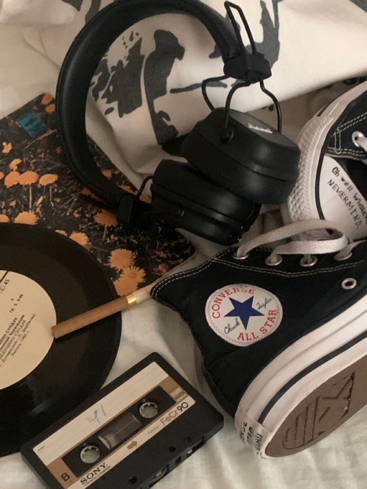 an old record, headphones, and pair of sneakers are laying on a bed