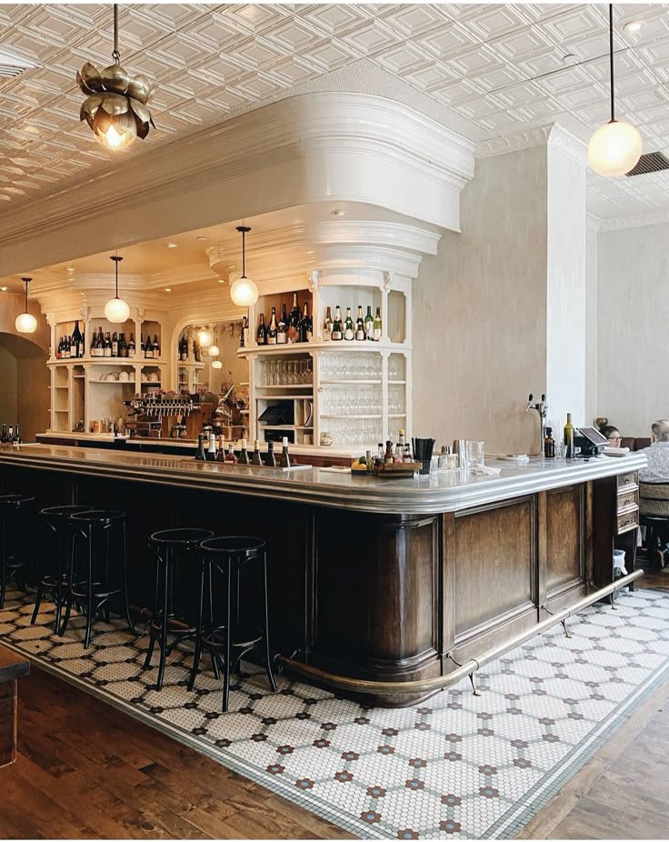 a bar with several stools in front of it and lights hanging from the ceiling