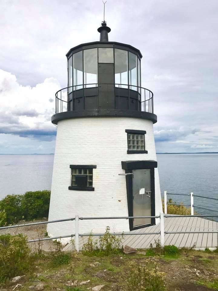 a white and black lighthouse sitting on top of a hill